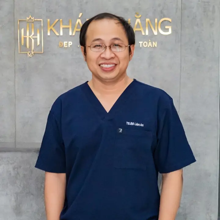 BS An mặc áo phẫu thuật, đứng trước biển hiệu phòng khám